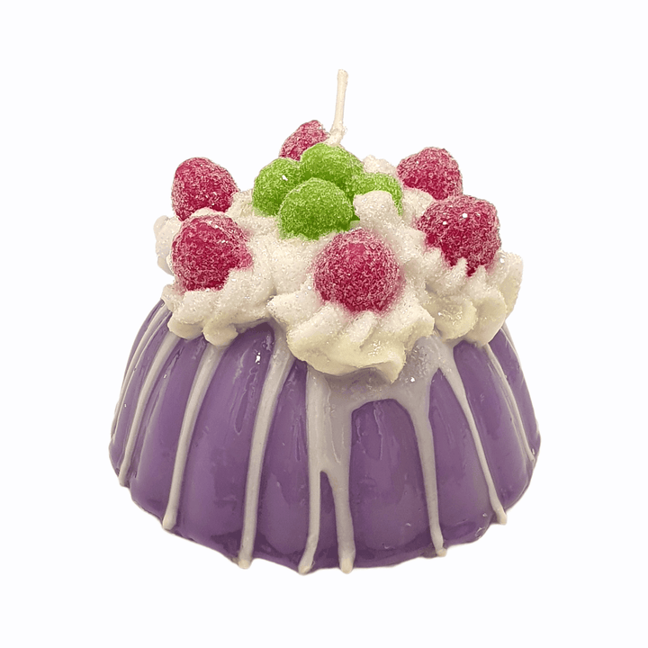 Lila Kerze in Puddingform mit weißer Verzierung und bunten Beeren, Glam Deko Codeso Living