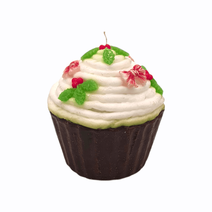 Weiße Weihnachtskerze im Cupcake-Design mit Deko aus Beeren und grünen Blättern