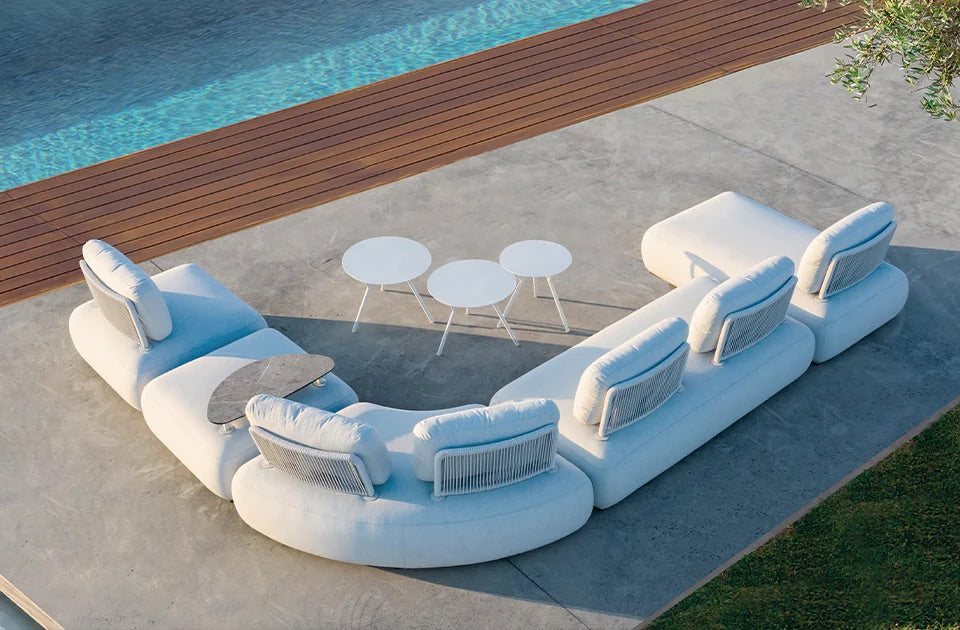 Moderne Outdoor Lounge mit weißem Sofa, runden Tischen und Pool am Codeso Living Luxusgarten