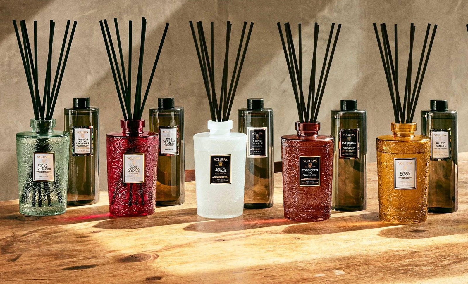 Voluspa Raumdüfte und Diffuser in eleganten, bunten Glasflakons auf Holztisch, Codeso Living