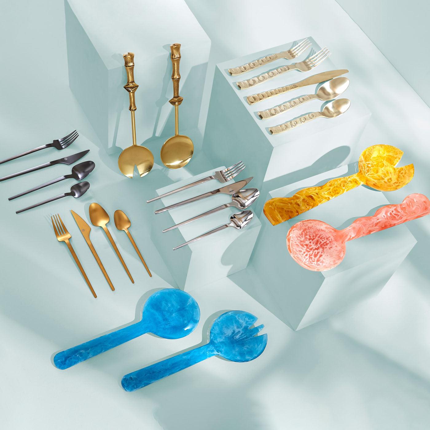 Stilvolles Besteck-Set in Gold, Silber, Schwarz und farbigem Acryl auf modernem Untergrund