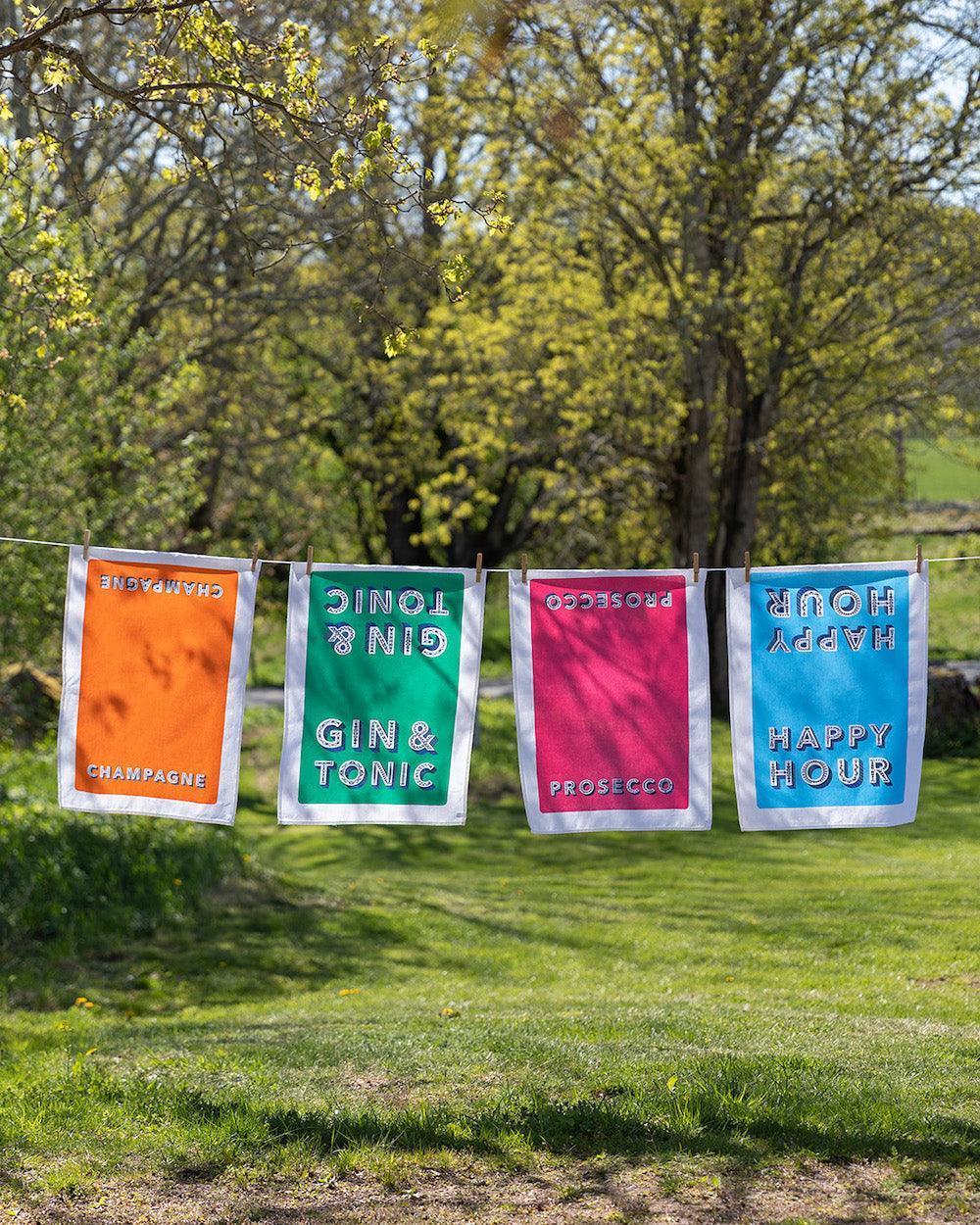 Bunte Geschirrtücher mit Aufdruck Champagne, Gin & Tonic, Prosecco und Happy Hour auf Leine im Garten