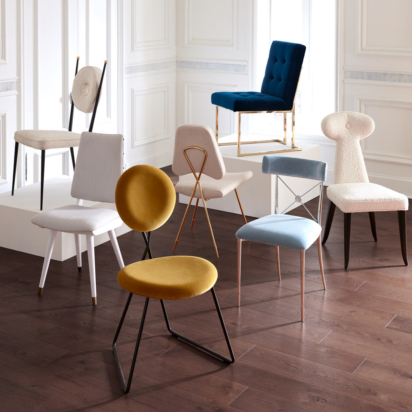 Moderne Esszimmerstühle von Jonathan Adler in verschiedenen Farben und Designs vor weißer Wand