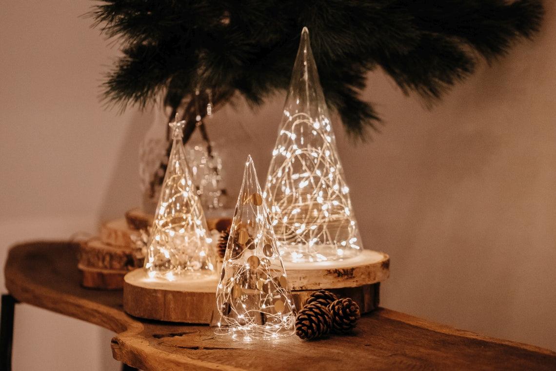 Stimmungsvolle Deko: LED-Lichterbäume aus Glas auf rustikalem Holz, Zapfen, glamouröses Interior