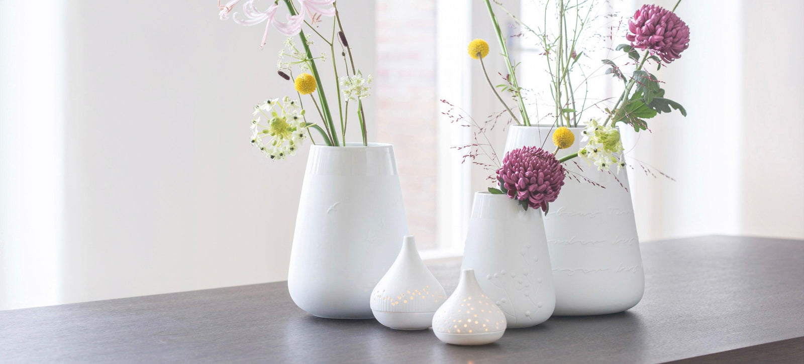Moderne weiße Räder Design Vasen mit Blumen und Teelichthaltern auf dunklem Tisch, Codeso Living