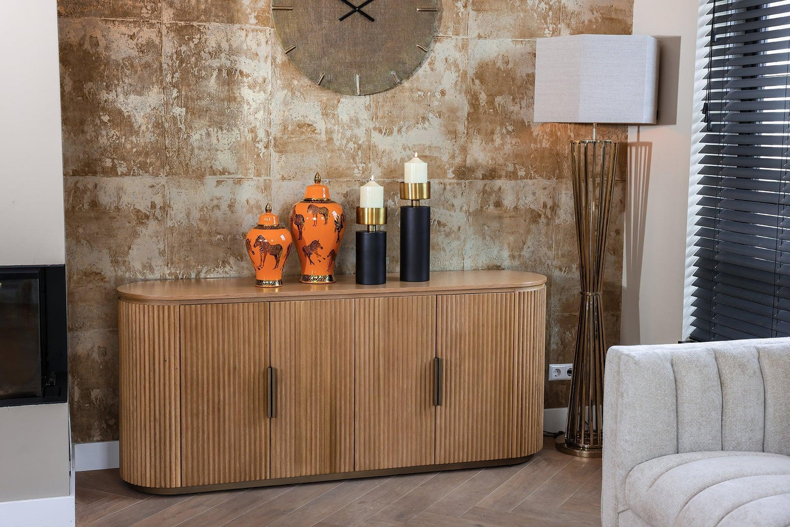 Richmond Interiors Belfort Sideboard aus Holz mit orangen Vasen und modernen Kerzenhaltern, stilvoll vor einer goldfarbenen Wand, Codeso Living Luxus Interior