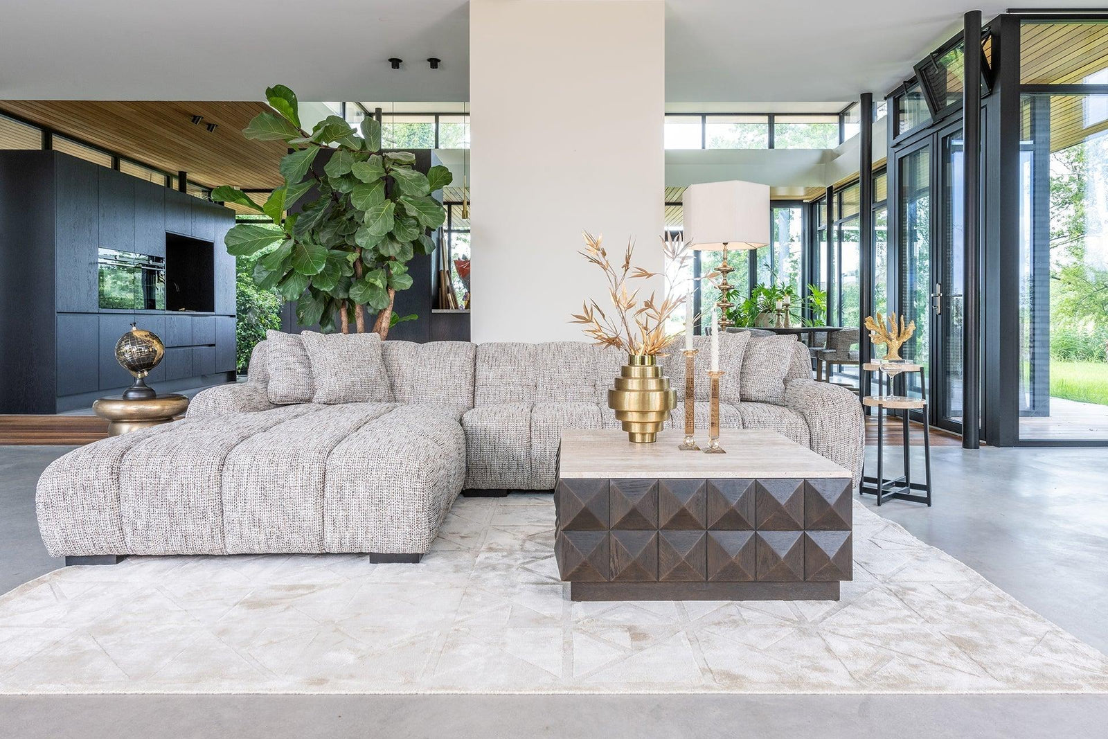 Modernes Wohnzimmer mit luxuriösem Ecksofa, Design-Couchtisch, goldenen Deko-Accessoires und großen Fenstern