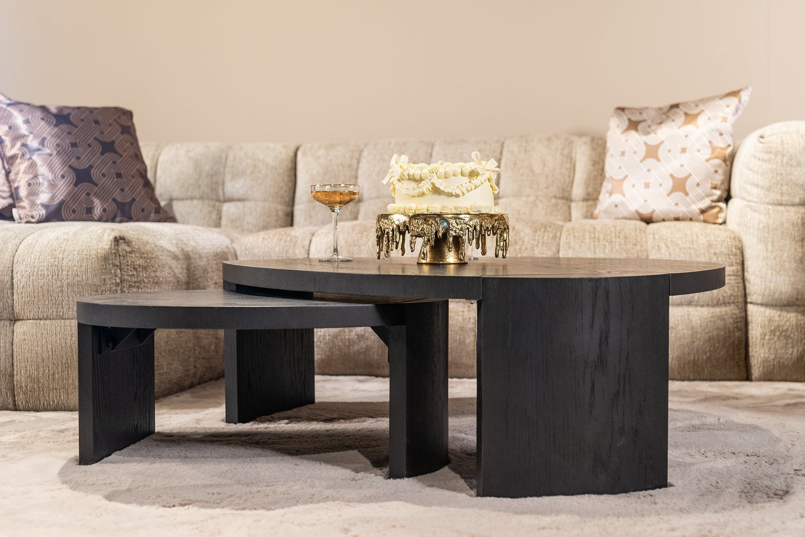 Modernes Wohnzimmer mit beigen Sofa, Deko-Kissen und schwarzen Couchtischen von Codeso Living