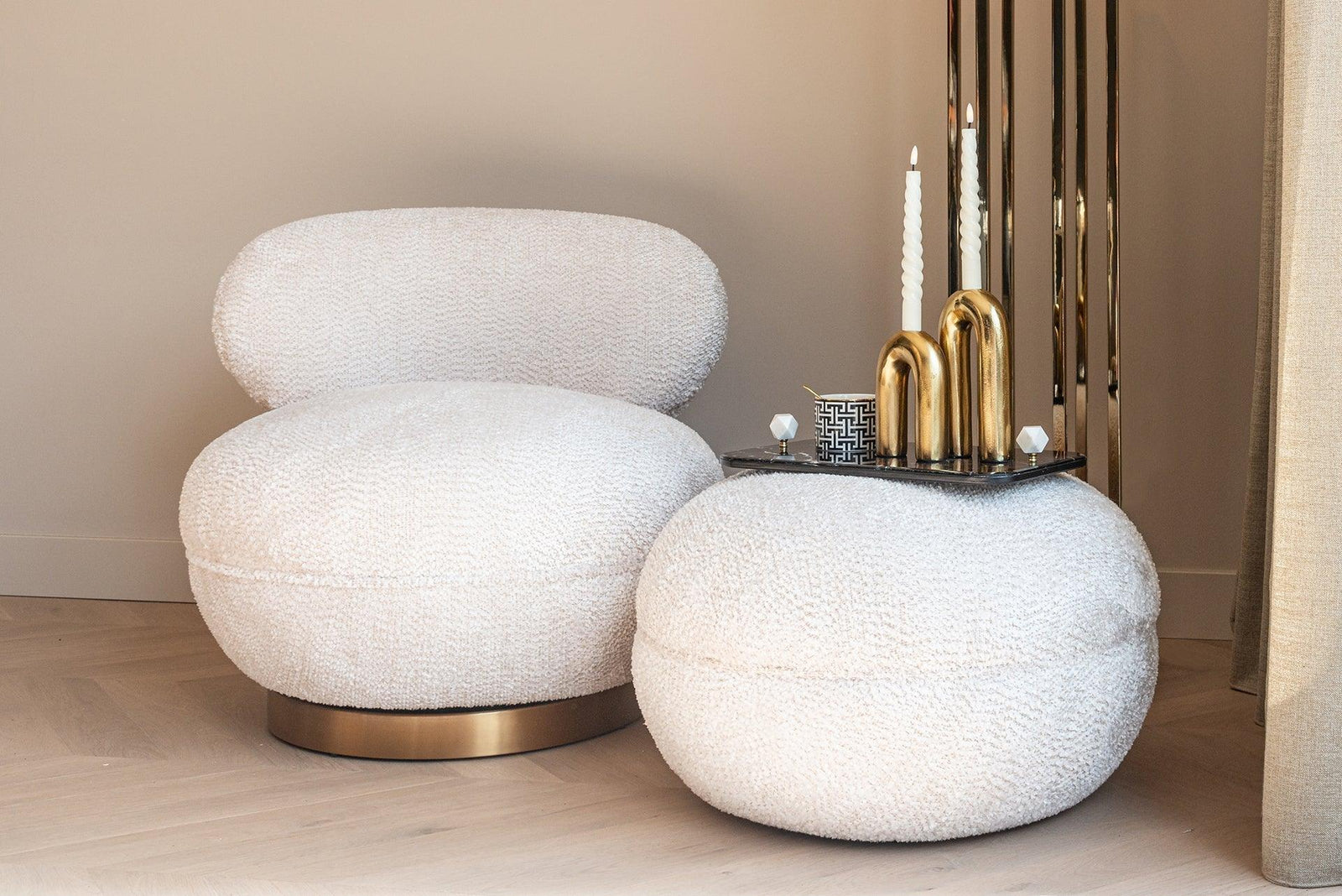 Moderner Bouclé-Sessel in Creme mit goldenen Deko-Kerzen im Codeso Living Luxus-Interior