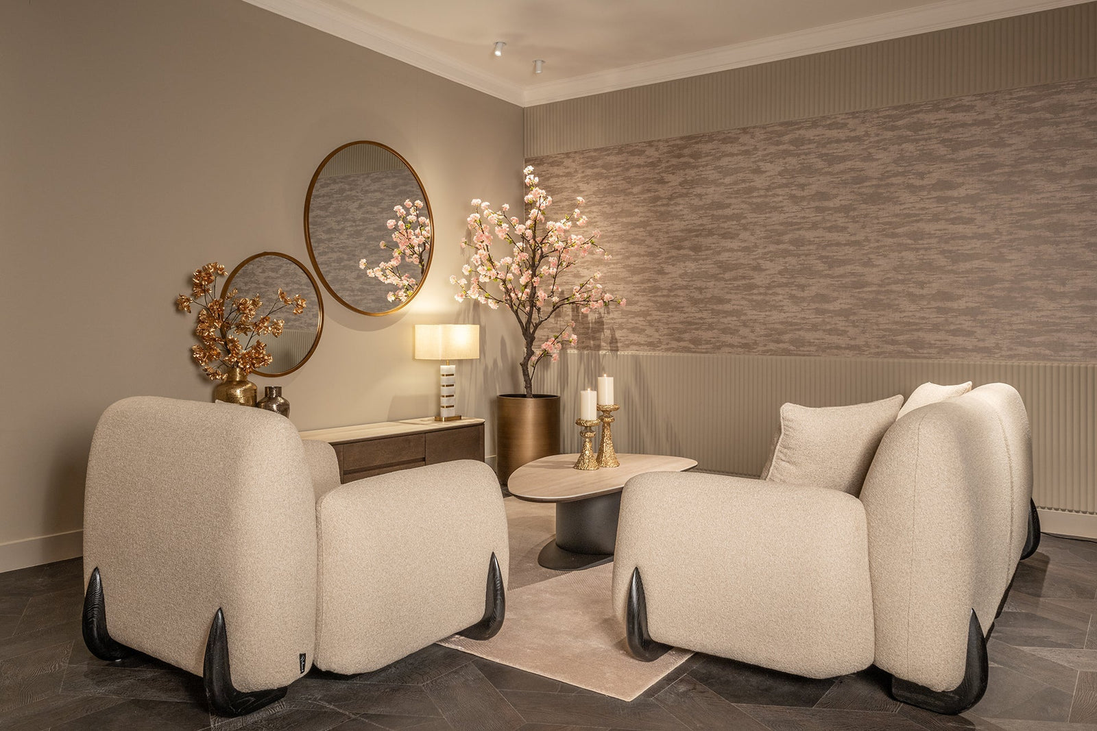 Elegantes Wohnzimmer mit runden Spiegeln, beigen Designer-Sofas, Blütenzweigen und goldenen Deko-Elementen im Codeso Living Maximalismus-Stil.