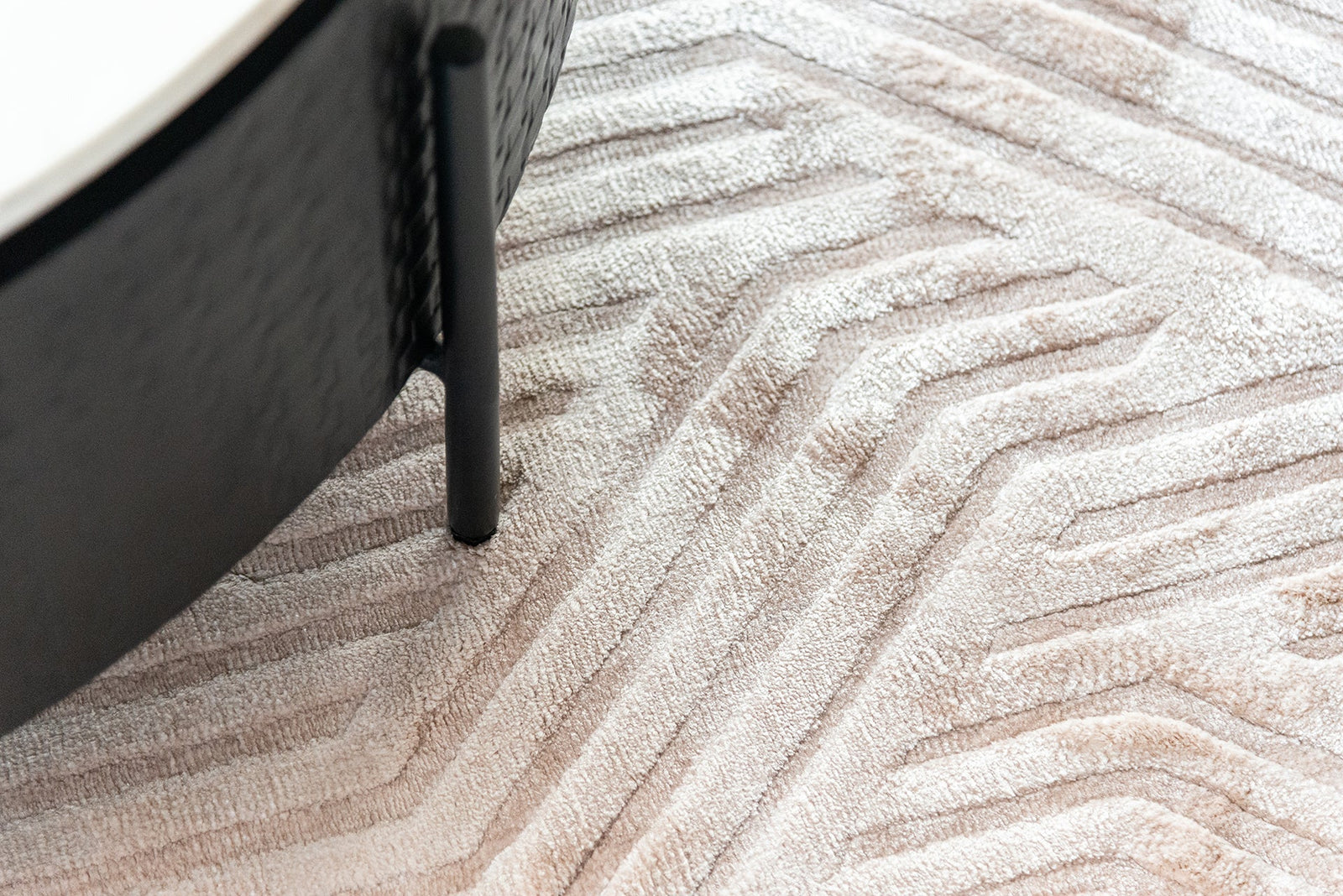 Moderner beiger Teppich mit geometrischem Muster und schwarzem Couchtischbein, Codeso Living