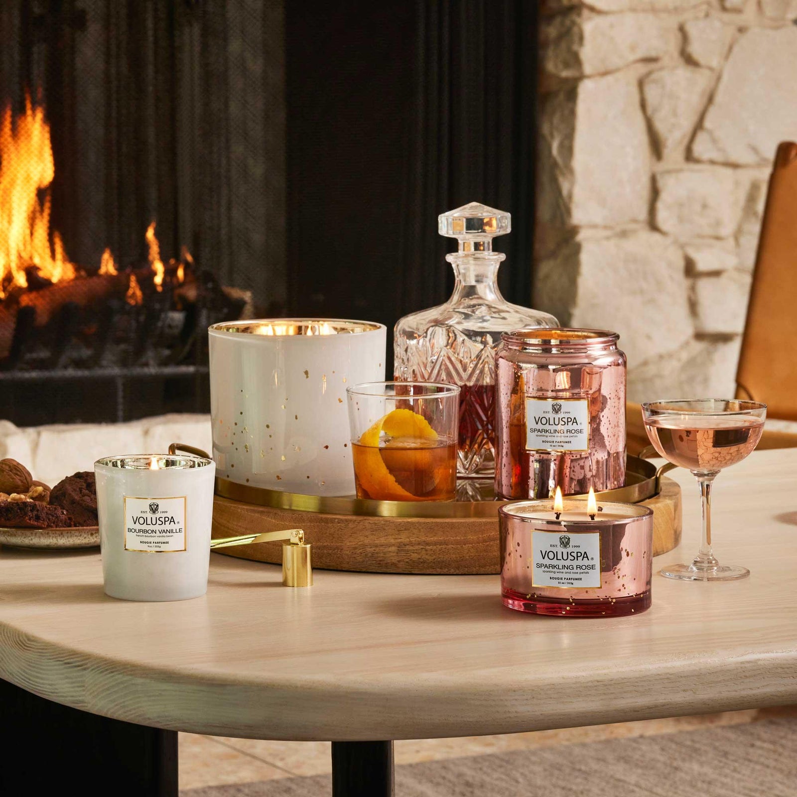 Voluspa Vermeil Duftkerzen auf Holztisch vor Kamin, luxuriöses Interior von Codeso Living
